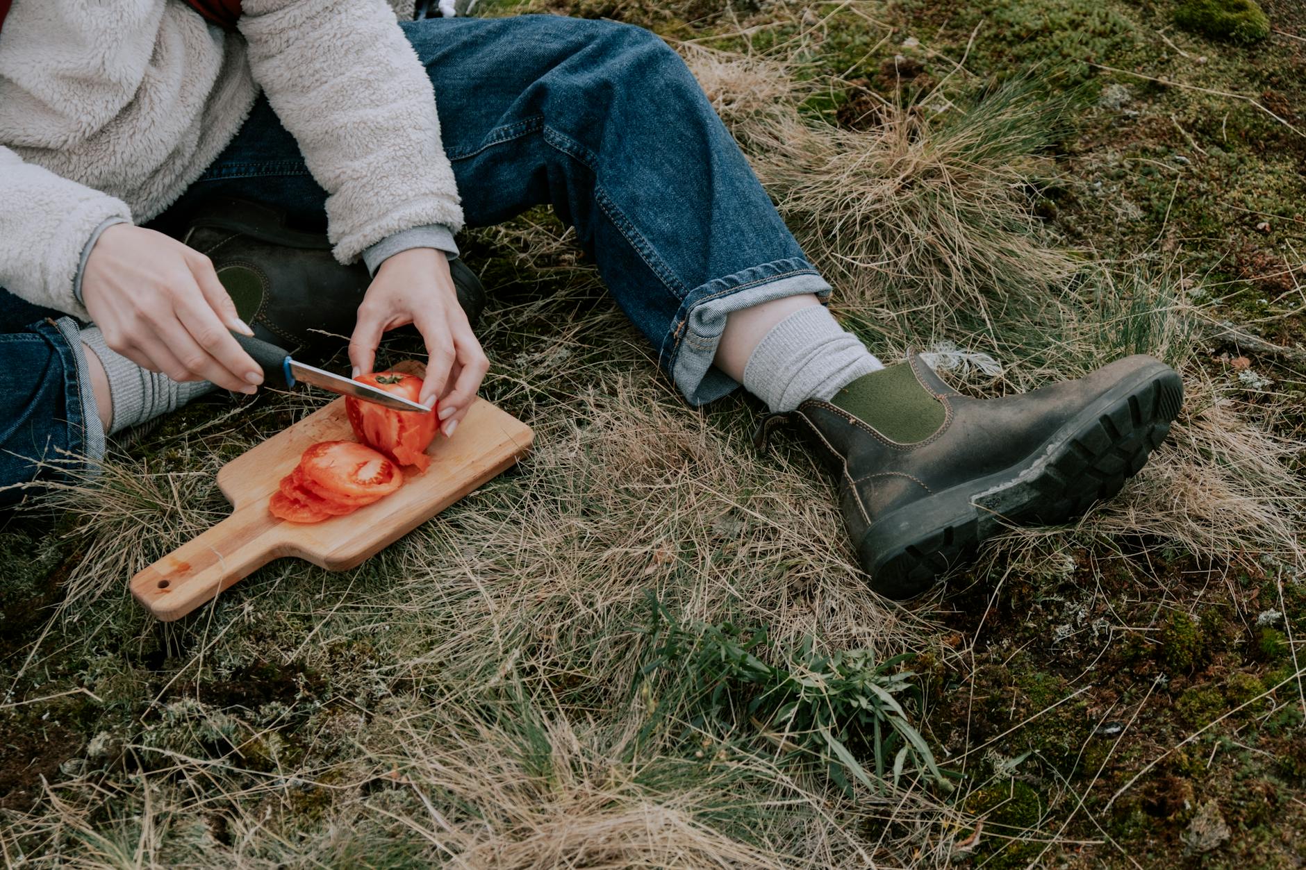 person in blue jeans sitting on grass