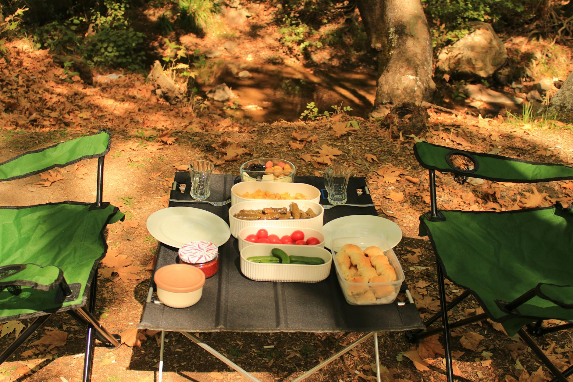 outdoor picnic setup with green chairs and snacks