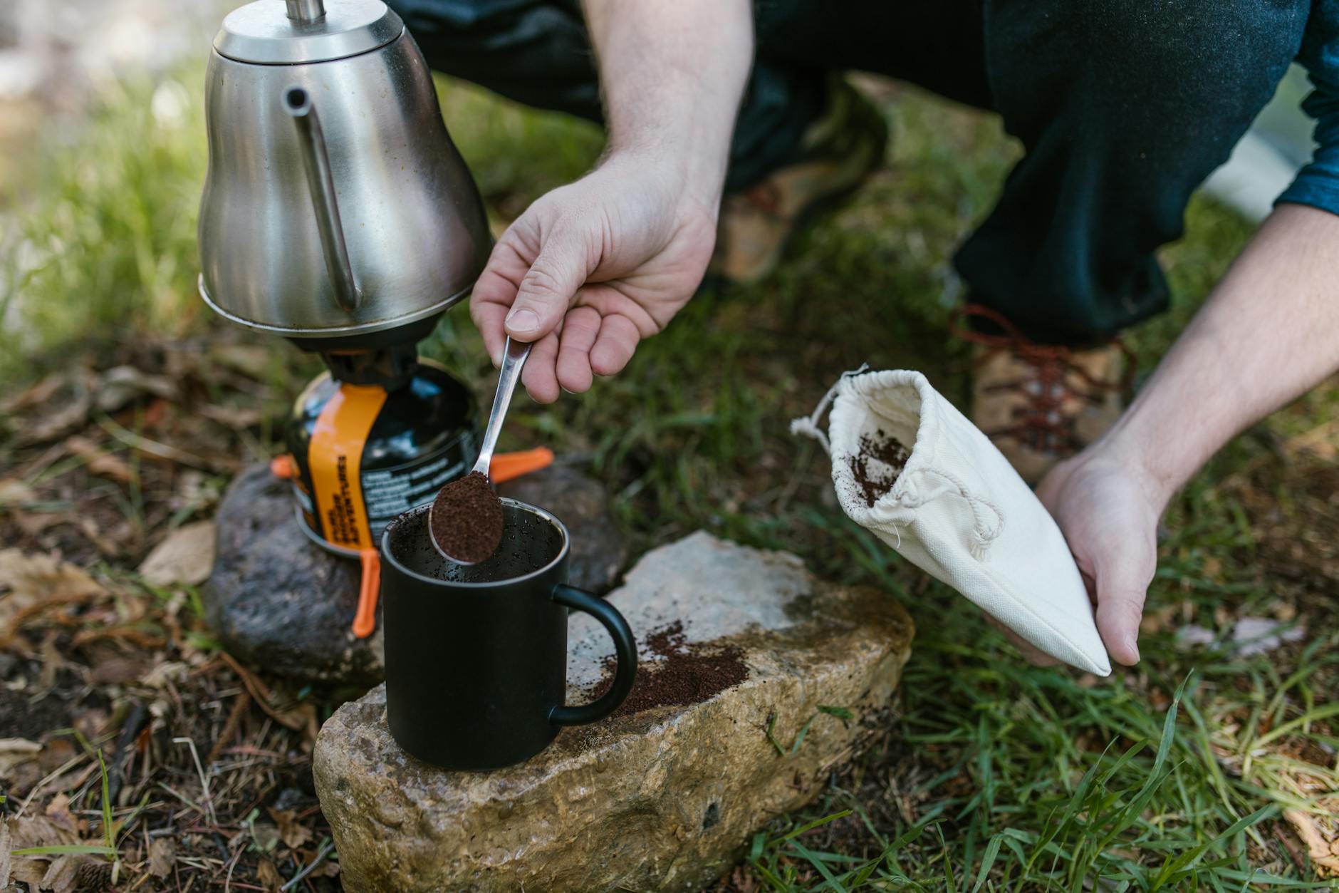 person holding stainless steel teapot pouring black ceramic mug